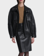 Women's oversized black lambskin bomber worn open over a tan knit, front view, with the stand collar folded and snaps showing