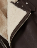 Close-up of the cream shearling lapel, buckle strap and YKK zip on the men's dark brown aviator jacket