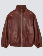 Women's oversized brick red leather bomber jacket laid flat, front view, with a stand collar, center zip and snapped flap pockets