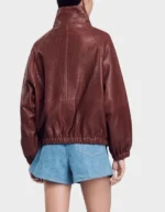 Back view of the women's oversized brick red leather jacket on a model, showing raglan seams and the elastic gathered hem
